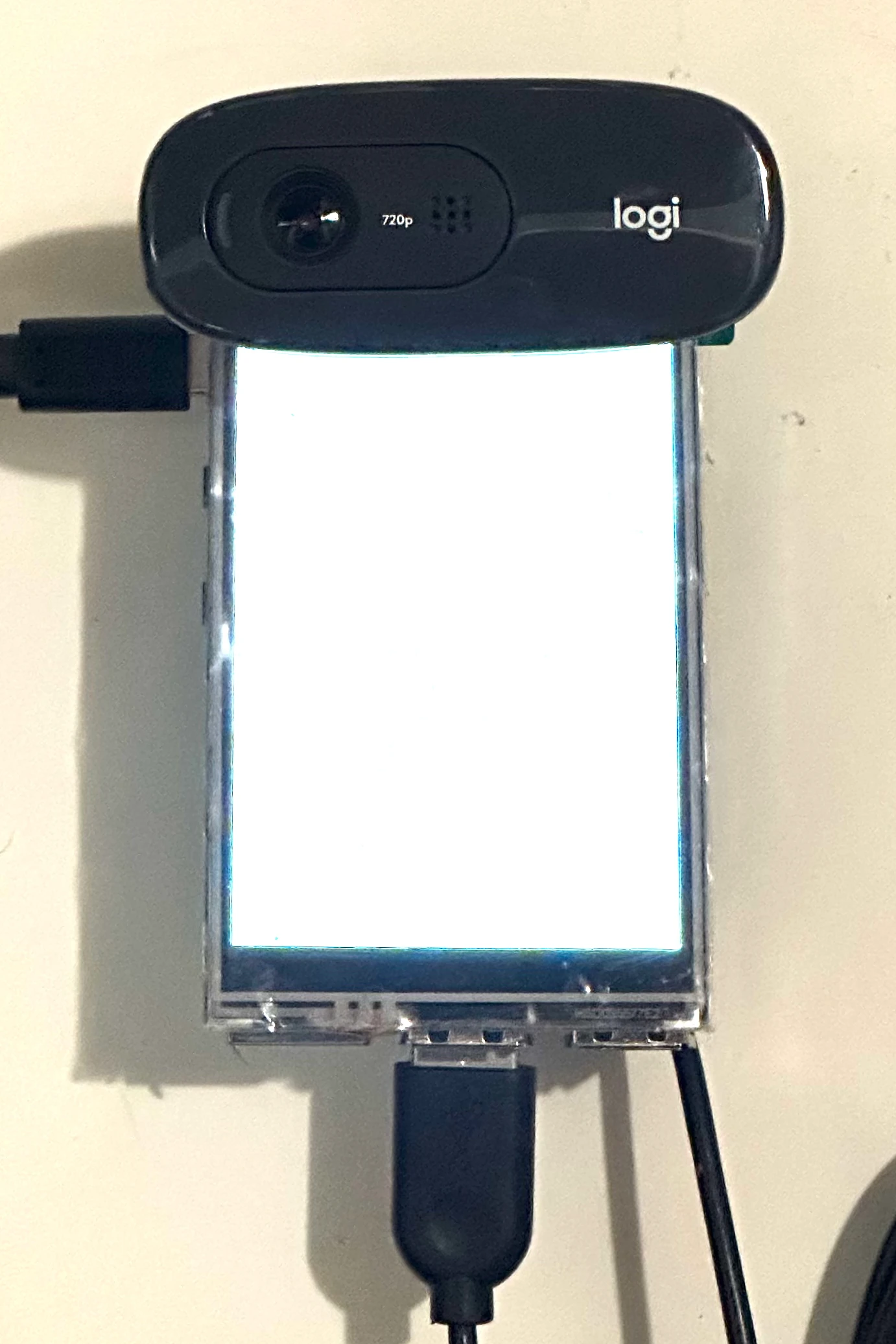The assembled device lit up, with a Logitech webcam on top and a power cable attached